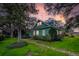 Charming green two-story home with lush landscaping and stone pathway during a colorful sunset at 10350 54Th N Ave, St Petersburg, FL 33708