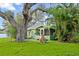 Quaint green home with lush lawn, mature trees, and charming screened-in porch at 10350 54Th N Ave, St Petersburg, FL 33708
