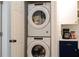 Convenient laundry area includes stacked washer and dryer units, alongside dark blue cabinets and white shiplap walls at 10350 54Th N Ave, St Petersburg, FL 33708