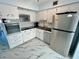 White kitchen cabinets and black counter tops, stainless steel refrigerator and modern marble-patterned floors at 2311 Brisbane St # 65, Clearwater, FL 33763