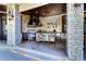 Outdoor kitchen with stone columns features a built-in grill, exhaust hood, bar seating, and a TV at 200 Brightwaters Ne Blvd, St Petersburg, FL 33704