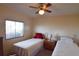 A cozy bedroom includes two twin beds, nightstand, fan and a window at 37642 Amigo Dr, Zephyrhills, FL 33541