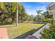 Spacious backyard with lush greenery, palm trees, and a paved walkway at 4251 Whittner Dr, Land O Lakes, FL 34639