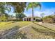 Spacious backyard with grassy area, palm trees, and a brick pathway at 4251 Whittner Dr, Land O Lakes, FL 34639