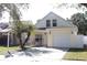 Charming two-story home featuring a light yellow exterior, single car garage, and a cozy front porch with rocking chairs at 5607 Tanagergrove Way, Lithia, FL 33547