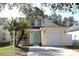 Charming two-story home featuring a light yellow exterior, single car garage, and a cozy front porch with rocking chairs at 5607 Tanagergrove Way, Lithia, FL 33547