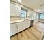 Bright kitchen with white cabinetry, stainless steel dishwasher, and wood-look flooring at 5611 Riddle Rd, Holiday, FL 34690