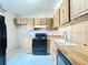 Kitchen featuring wood cabinets, black appliances, light countertops, and tile floors at 6441 Drexel Dr # 7, Port Richey, FL 34668