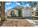 Gray house with white garage door, landscaping, and a large tree in the front yard at 7503 Wakulla Dr, Temple Terrace, FL 33637