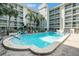 Large pool with ample seating, adjacent to condominium building and tropical landscaping at 801 83Rd N Ave # 217, St Petersburg, FL 33702