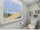 Bathroom with a toilet by the window that provides natural light with shell decor on the wall at 952 Symphony Isles Blvd, Apollo Beach, FL 33572