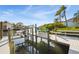 Boat dock with a boat lift, and a small boat sitting in the lift on a sunny day surrounded by lush greenery at 952 Symphony Isles Blvd, Apollo Beach, FL 33572