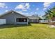 Backyard view showing the lush green lawn, covered lanai, and wood deck seating area at 9942 56Th Way, Pinellas Park, FL 33782