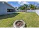 Expansive backyard with lush lawn, mature palms, white vinyl fence, and cozy fire pit at 9942 56Th Way, Pinellas Park, FL 33782