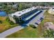 Aerial view of the condo building with covered parking, surrounded by green spaces and residential areas at 1450 Heather Ridge Blvd # 305, Dunedin, FL 34698