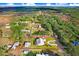 Aerial view of a charming home featuring a long driveway, mature trees, lush lawn and screened pool at 1702 W Knights Griffin Rd, Plant City, FL 33565