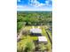 Aerial view of home with long drive, mature trees, screened pool, and large outbuilding at 1702 W Knights Griffin Rd, Plant City, FL 33565