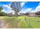 Exterior view of home and outbuilding with fenced perimeter, blue skies, and green grass at 1702 W Knights Griffin Rd, Plant City, FL 33565