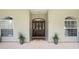 Elegant front entrance with a decorative wood door, sidelights, and potted plants at 1702 W Knights Griffin Rd, Plant City, FL 33565