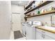 Laundry room with wood shelves, white cabinets, washer, dryer, and a utility sink at 1702 W Knights Griffin Rd, Plant City, FL 33565