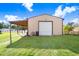 Outbuilding with a large roll-up door and attached carport on a sunny day at 1702 W Knights Griffin Rd, Plant City, FL 33565