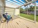 Charming backyard patio with wood flooring, a pergola, blue chairs, and a view of the green lawn at 212 S Himes Ave, Tampa, FL 33609