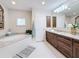 Bathroom featuring a soaking tub, white tile floors, and dark wood cabinets at 212 S Himes Ave, Tampa, FL 33609