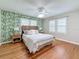 Charming bedroom featuring wood floors, tropical wallpaper, shutters, and a ceiling fan for optimal comfort at 212 S Himes Ave, Tampa, FL 33609