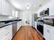 Galley kitchen featuring white cabinets, stainless steel appliances, subway tile backsplash, and hardwood floors at 212 S Himes Ave, Tampa, FL 33609