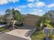 Tan two-car garage villa with paver driveway, landscaping, and palm trees at 2416 Kensington Greens Dr # 2416, Sun City Center, FL 33573