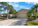 Tan two-car garage villa with paver driveway and mature landscaping at 2416 Kensington Greens Dr # 2416, Sun City Center, FL 33573