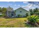 Backyard view of the home featuring a screened-in patio and lush landscaping at 3710 Rain Tree Ct, Palm Harbor, FL 34685