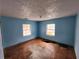 A bedroom with blue walls, damaged flooring, and exposed support beams at 6502 S Himes Ave, Tampa, FL 33611