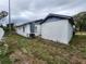 Side view of a small house needing repairs, with overgrown yard at 6502 S Himes Ave, Tampa, FL 33611