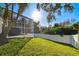 Landscaped backyard with a screened pool and white fence at 714 Hidden Lake Dr, Tarpon Springs, FL 34689