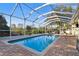 Sparkling pool with a screened enclosure and brick pavers at 714 Hidden Lake Dr, Tarpon Springs, FL 34689