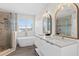 Elegant bathroom featuring a soaking tub, glass shower, double vanity with framed mirrors, and window shutters at 8619 Foxtail Ct, Tampa, FL 33647