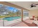 Covered patio with brick flooring, ceiling fan, and view of the screened-in pool and scenic backyard at 8619 Foxtail Ct, Tampa, FL 33647