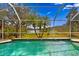 View of the in-ground swimming pool with a screened enclosure looking out to a scenic backyard and lake at 8619 Foxtail Ct, Tampa, FL 33647