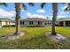 House's backyard with grassy lawn, palm trees, and partial view of house at 1252 Lyndhurst Greens Dr, Sun City Center, FL 33573