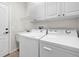 Bright laundry room with washer, dryer, cabinets, and utility sink at 1252 Lyndhurst Greens Dr, Sun City Center, FL 33573