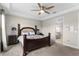 Spacious main bedroom with a dark wood bed frame, ceiling fan and a view into the bathroom at 13182 Twin Bridges Dr, Riverview, FL 33579