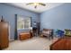 Spare bedroom featuring blue walls, window, wood furniture and neutral carpet at 18026 Macy Rd, Weeki Wachee, FL 34614