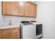 Bright laundry room with wood cabinets and modern appliances at 33843 Galley Way, Wesley Chapel, FL 33543