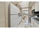 Galley kitchen with white appliances and view into dining area at 644 Island Way # 206, Clearwater, FL 33767