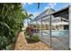 A brick walkway leading to a screened pool area, lined with lush tropical plants at 7566 Links Ct, Sarasota, FL 34243