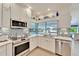 Bright kitchen with white cabinetry, stainless appliances, mosaic backsplash, and serene water view at 7566 Links Ct, Sarasota, FL 34243