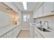 Bright laundry room with white cabinets, sink, and appliances, offering convenience at 7566 Links Ct, Sarasota, FL 34243