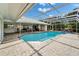 Screened-in pool area with brick pavers, an awning, and tropical landscaping at 7566 Links Ct, Sarasota, FL 34243