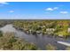 Aerial view highlighting waterfront living along a scenic river under a clear blue sky, with lush greenery at 906 W Henry Ave, Tampa, FL 33604